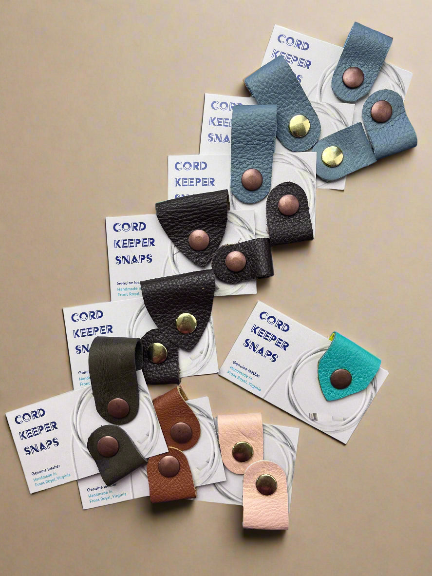Collection of colorful leather snap buttons on white cards with 'Cord Keeper Snaps' text against a blue background.