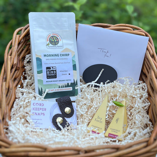 Wicker basket containing a small bag of coffee, two individual tea bags, leather cord keepers, and a thank you note.