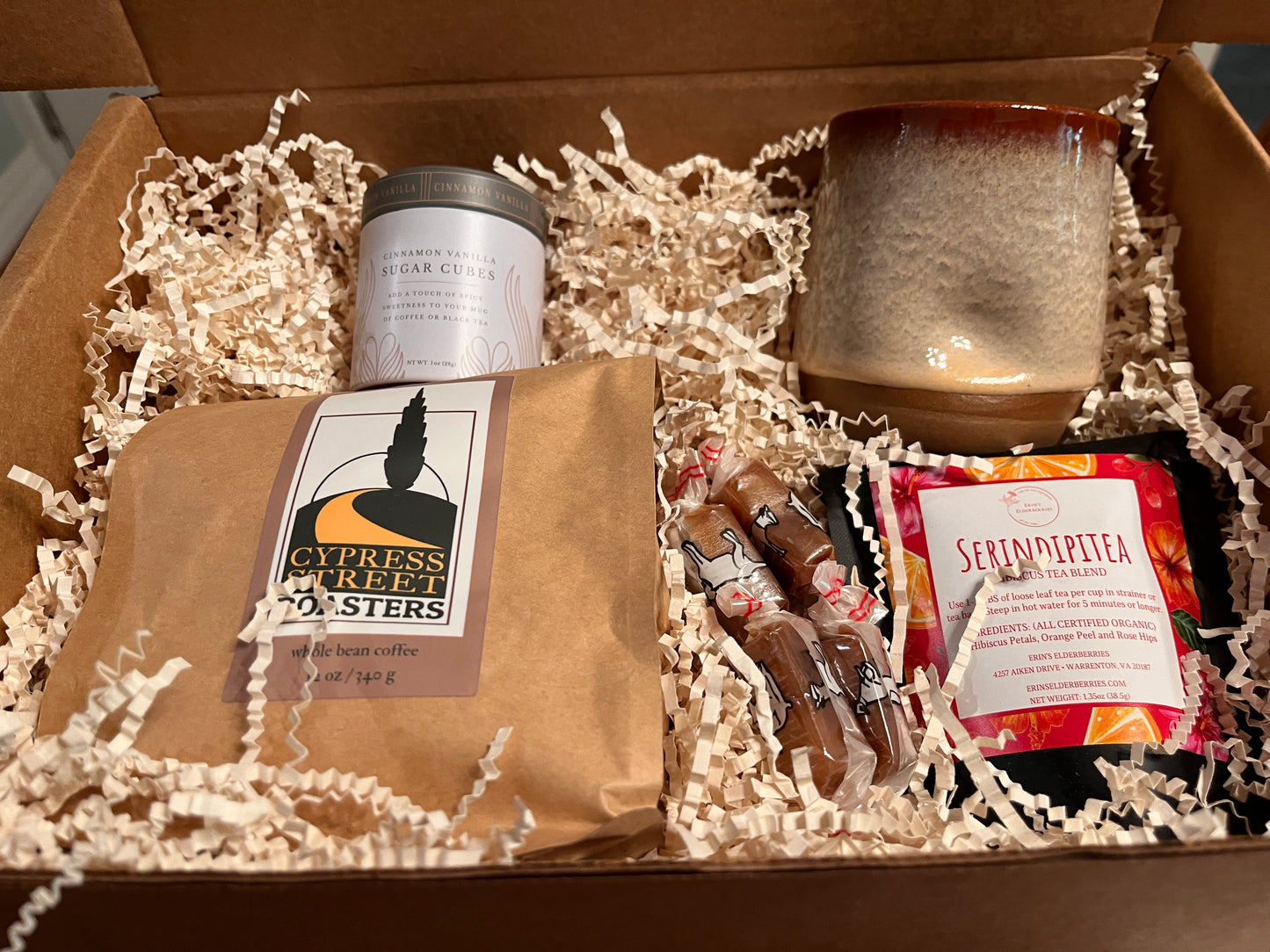 This image shows a thank you box containing  coffee, tea, a pottery mug and a sweetener.