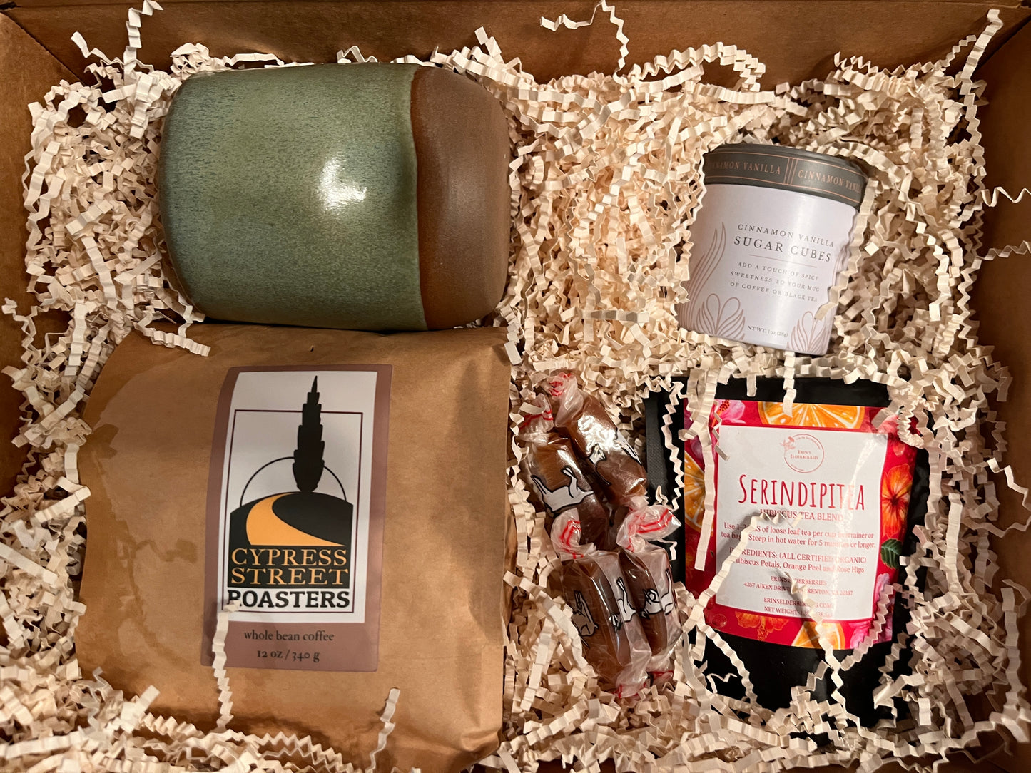 This image shows a thank you box containing  coffee, tea, a pottery mug and a sweetener.