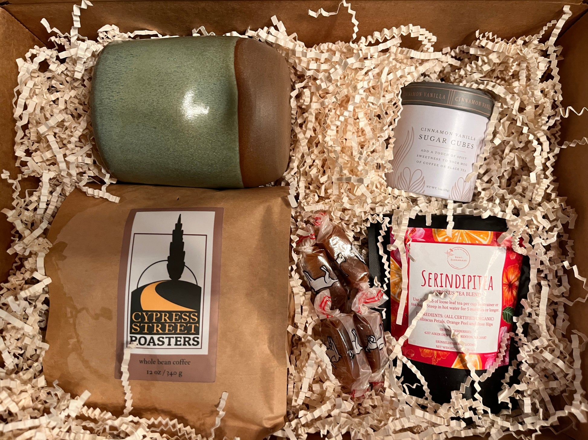 This image shows a thank you box containing  coffee, tea, a pottery mug and a sweetener.