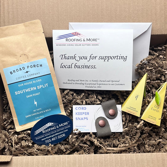 Open cardboard box with various items including a package, cards, and a small device on a textured surface.