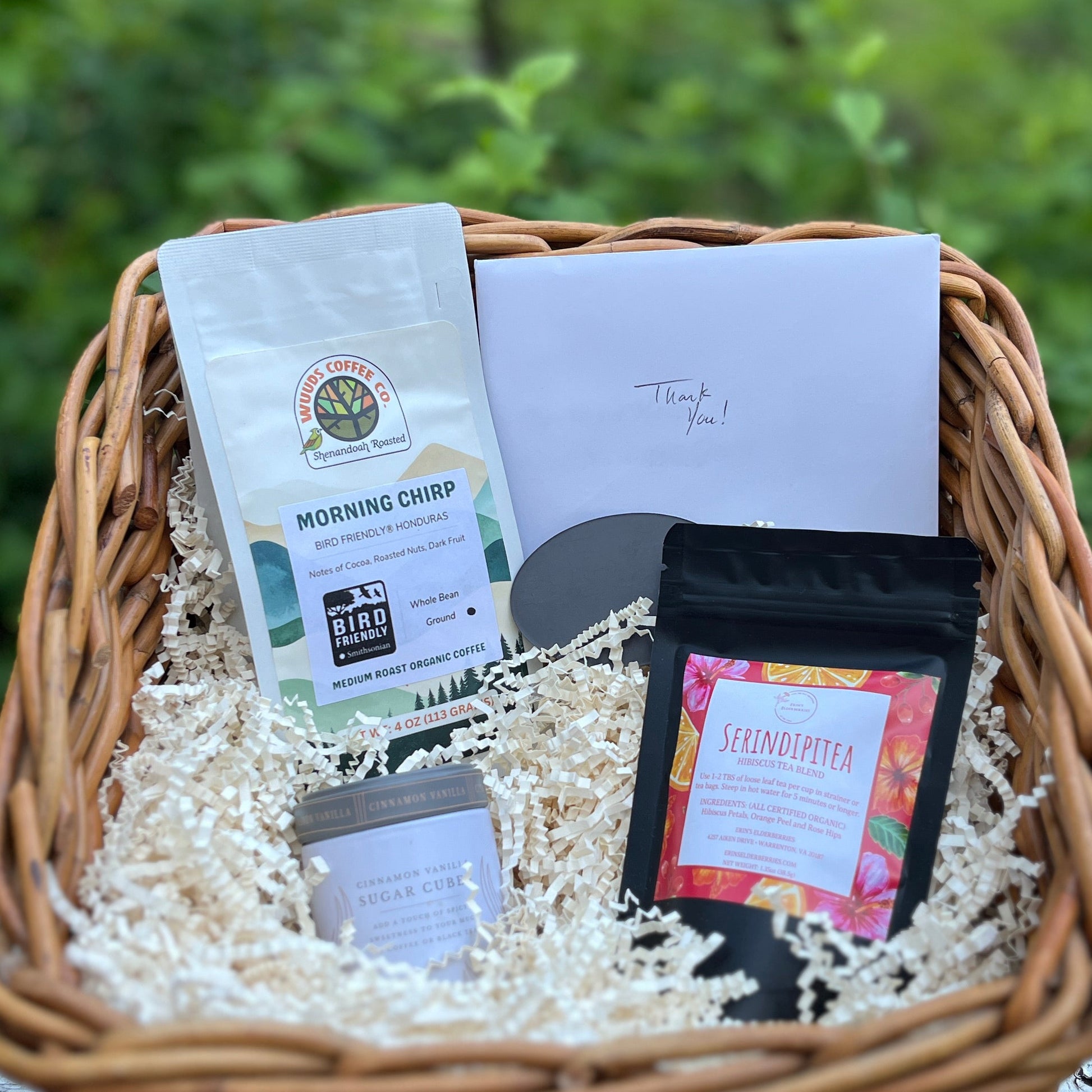 This image shows a wicker basket containing 4oz of coffee, tea, sugar cubes and a thank you card.