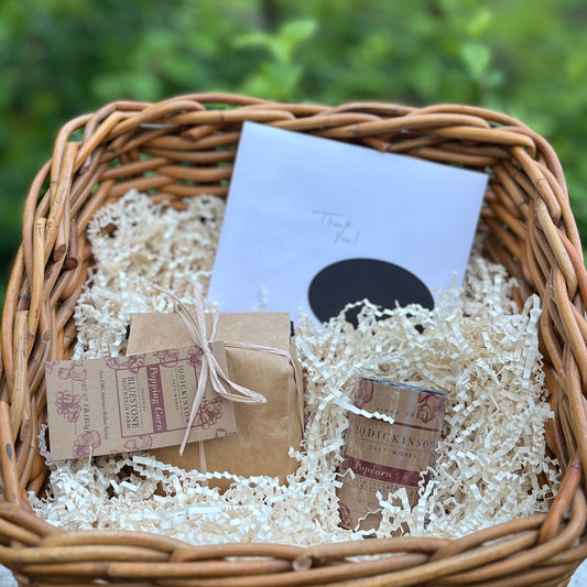 Wicker basket containing popcorn, popcorn salt and a thank you note.